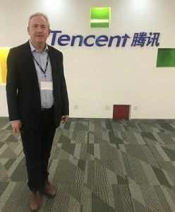 David Thomas standing beside the Tencent sign at the company's offices in 2019