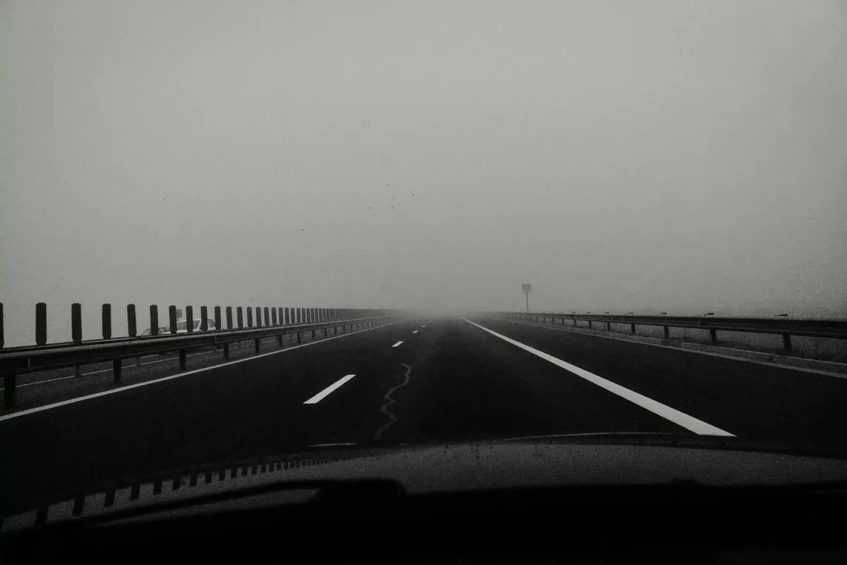 An empty road running into thick grey fog