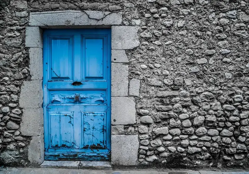 A weathered blue wooden door set in a rough stone wall
