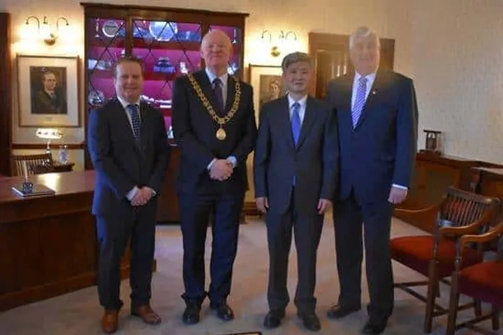 Four business and civic leaders standing together in a wood-panelled reception room