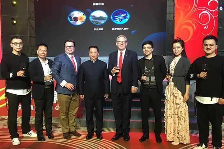 Guests photographed together on stage in front of a red event backdrop