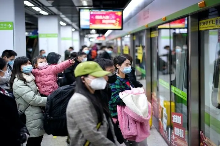 Commuters wearing face masks waiting on a metro platform