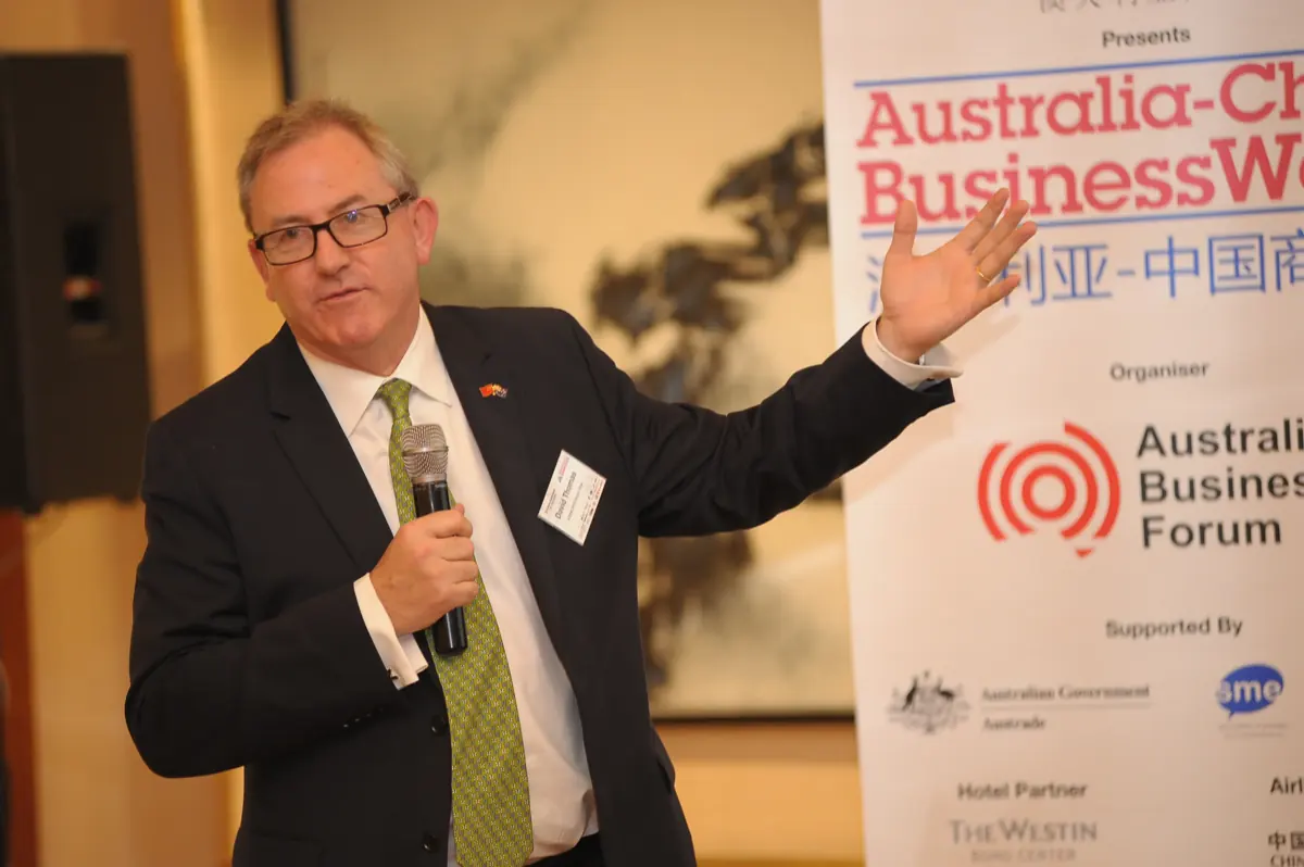 David Thomas addressing the Australia-China BusinessWeek forum, event banner behind him