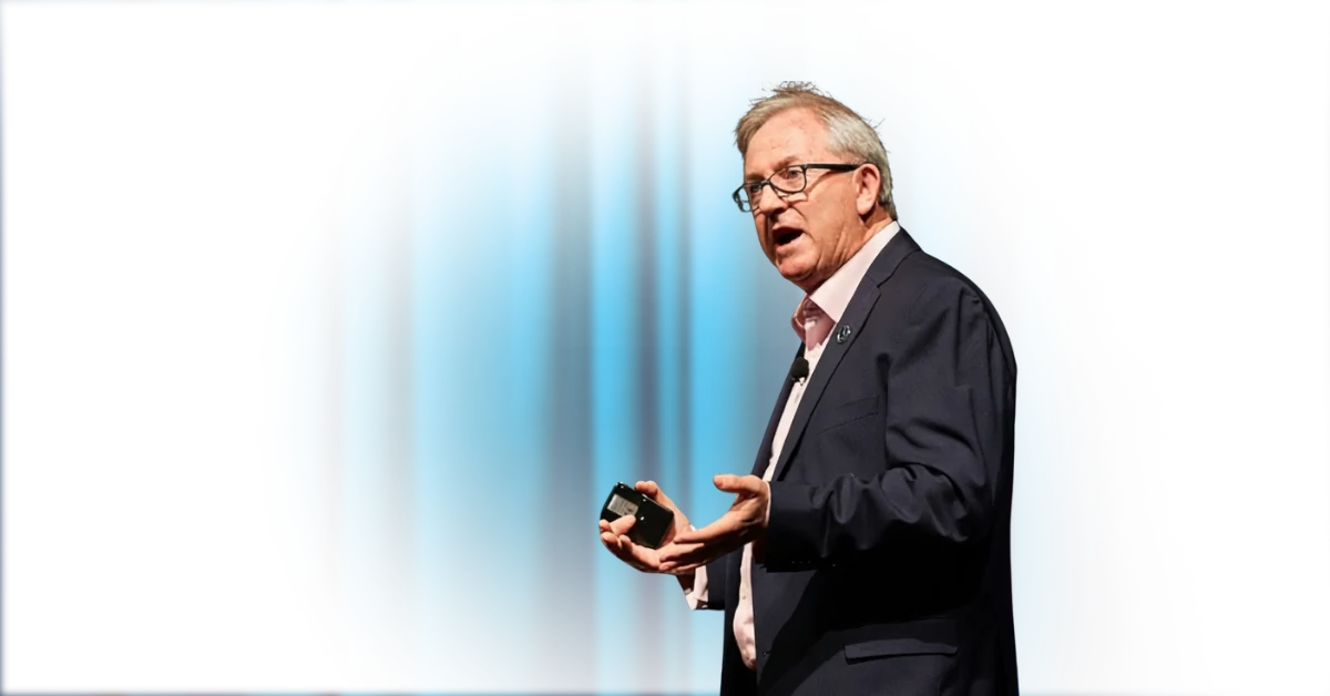 David Thomas speaking on stage, clicker in hand